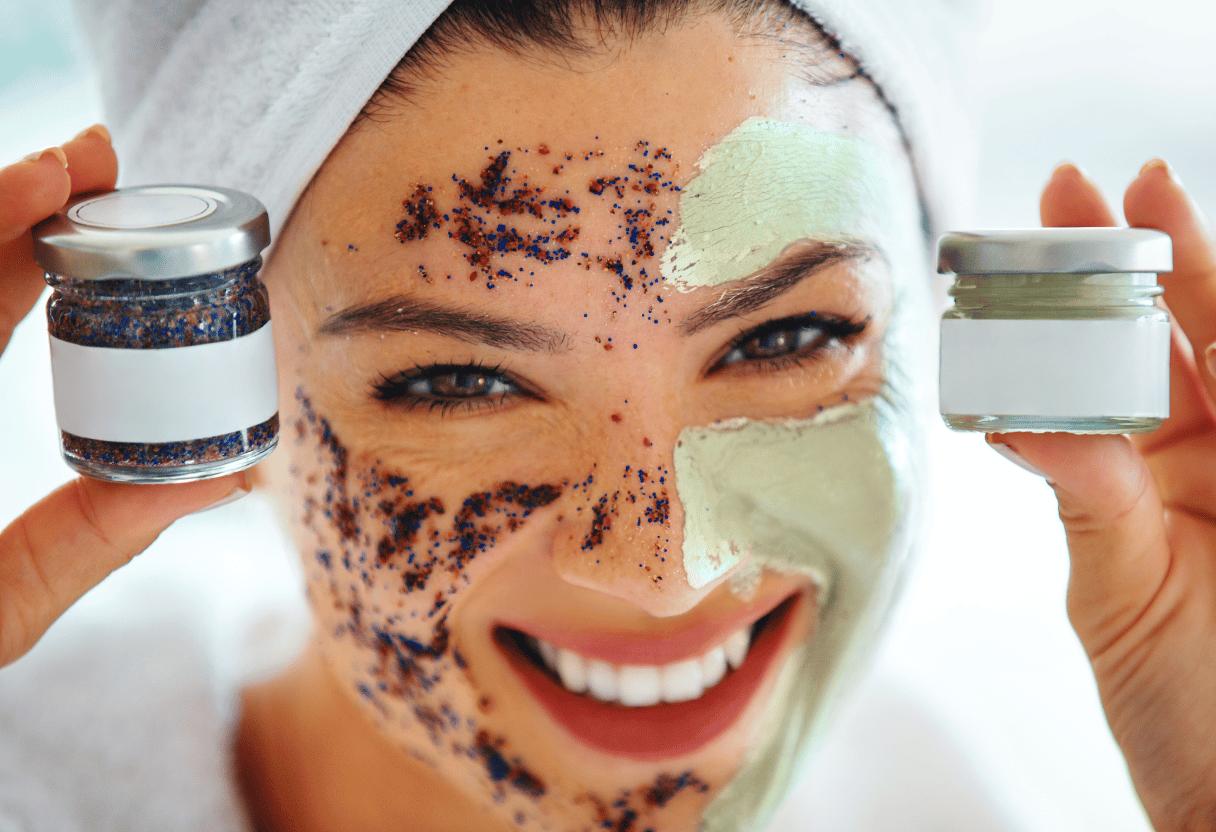 A smiling woman applying exfoliating scrub and clay mask