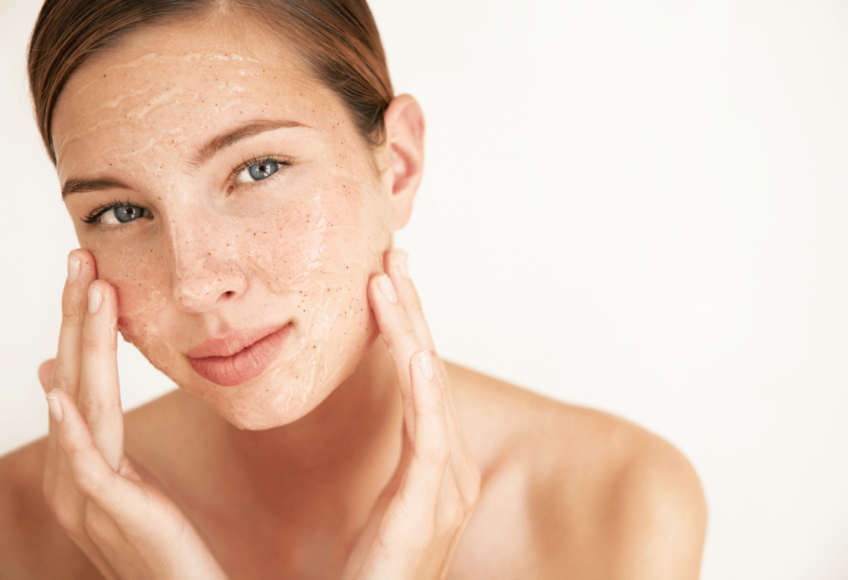A woman applying an exfoliating scrub to her face, showcasing smooth and radiant skin.