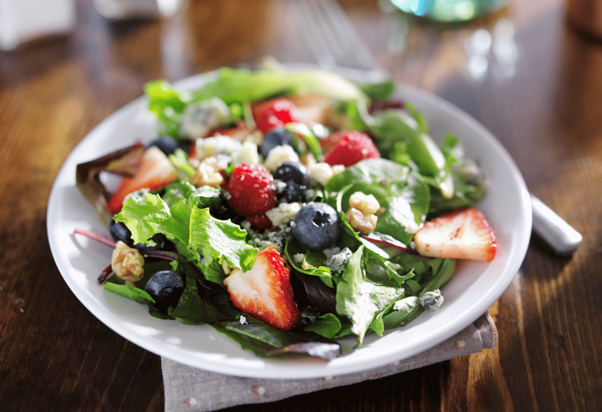 A plate of fresh salad with vibrant fruits and greens to promote healthy skin.