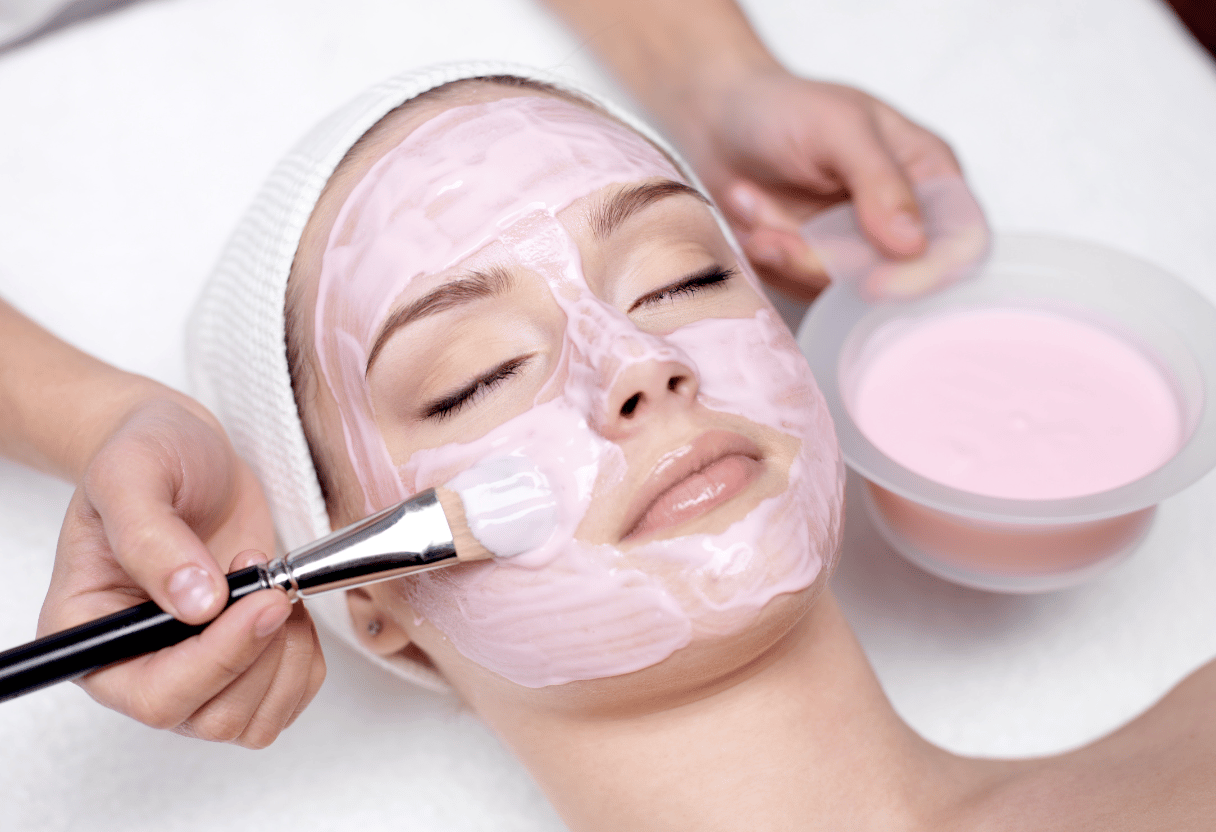 Woman lying down while a professional applies a pink mask