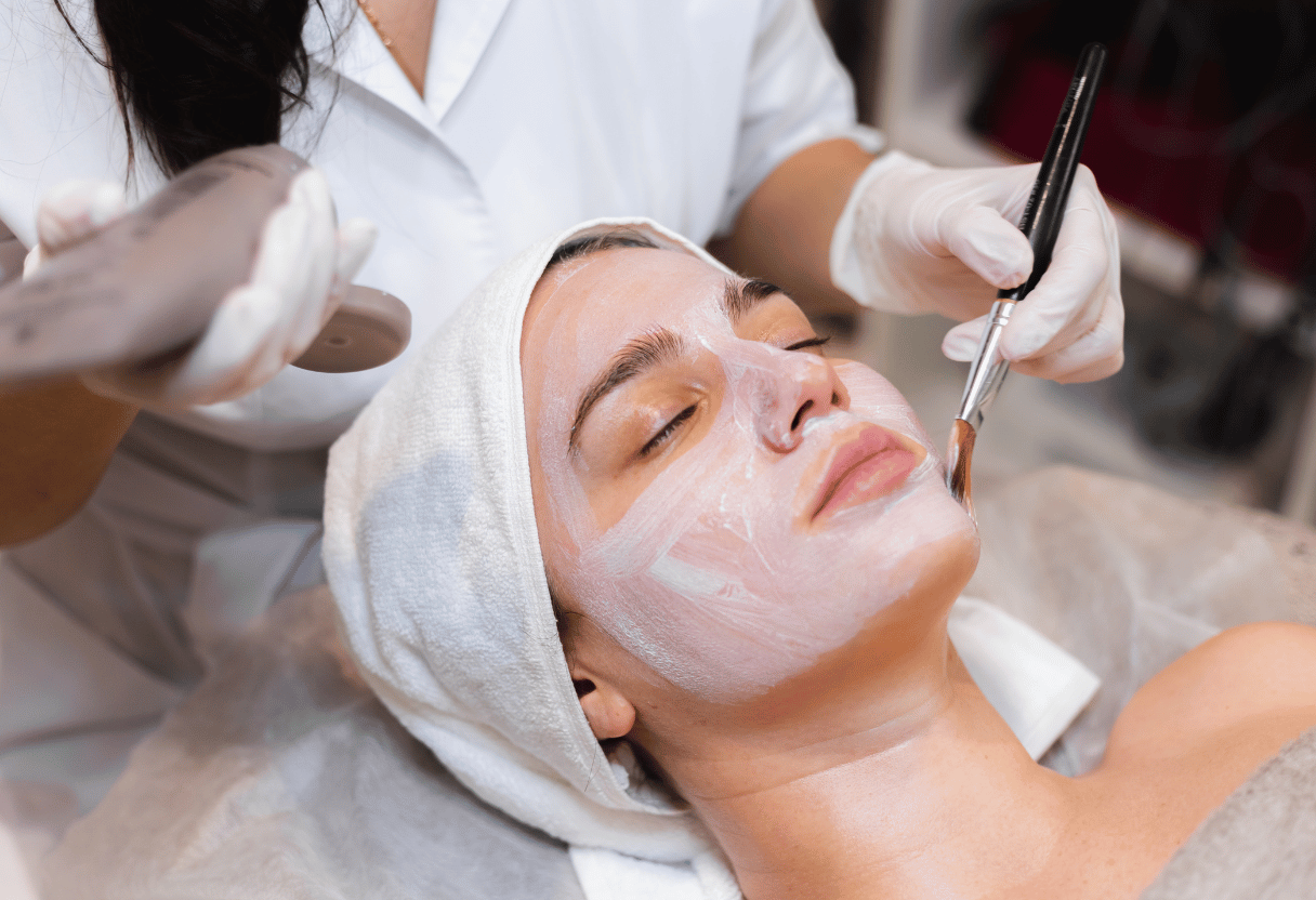 A woman receiving a professional facial treatment with a mask applied, emphasizing skincare routine benefits.